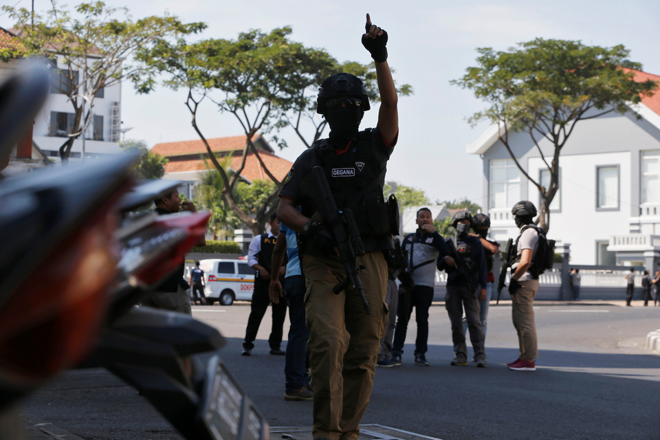 Policemen stand guard following a suicide bombing at the Surabaya Police headquarters in East Java on Monday (14/05). (Reuters Photo/Beawiharta)