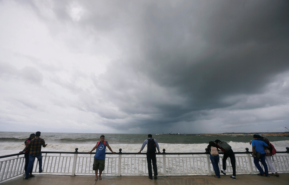 People look at the rough sea on a bridge as rainy clouds gather above during the monsoon period in Colombo, Sri Lanka, Monday (21/05) (Reuters Photo/Dinuka Liyanawatte)