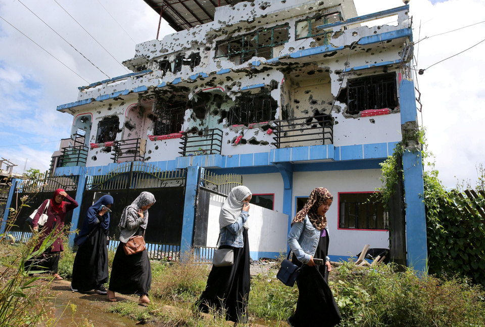 Residents who returned from evacuation centers walk past a bullet-ridden house believed to have been rented by pro-Islamic State militant group leaders Isnilon Hapilon and Omar Maute before their attack on the region, in Basak, Malutlut district in Marawi city, Philippines October 29, 2017.  (Reuters Photo/Romeo Ranoco)