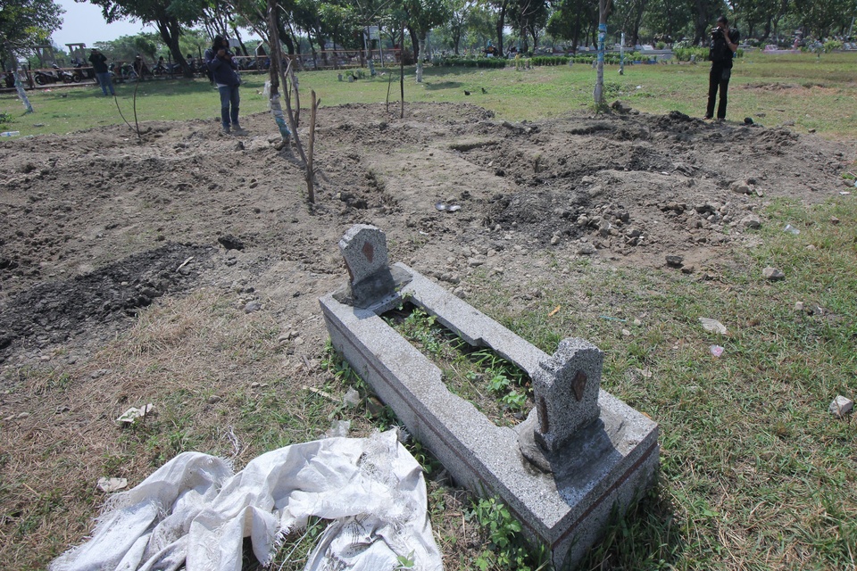A journalist photographs the graves dug for suicide bombers in Surabaya, East Java, on Friday (18/05). Local residents covered the empty graves in a refusal to bury the attackers who targeted three churches in the city last Sunday. (Antara Photo/Didik Suhartono)