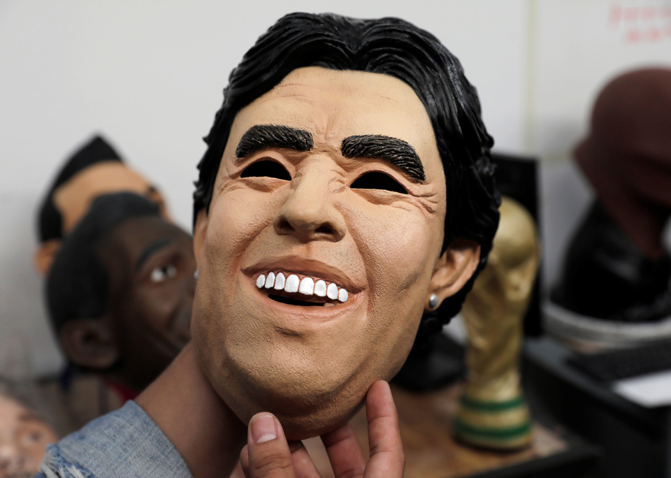 A man shows a mask in the likeness of former Argentina player Diego Maradona at a factory where the latex masks of 12 famous footballers are produced as World Cup fever grips the globe, in Cuernavaca, Mexico. (Reuters Photo/Henry Romero)