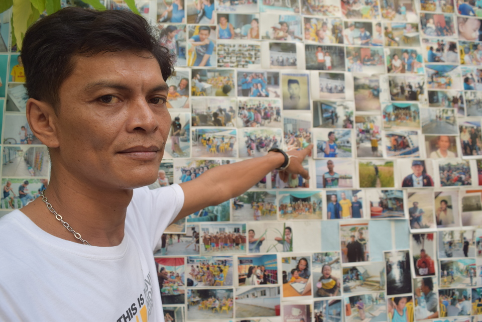 Chairat Ratchapaksi, who founded the Thai and Migrant Fishers Union Group to help trafficked fishermen like him, poses for a photo in front of pictures of rescued trafficking victims in Samut Sakhon, Thailand, March 25, 2018. (Reuters Photo/Beh Lih Yi)