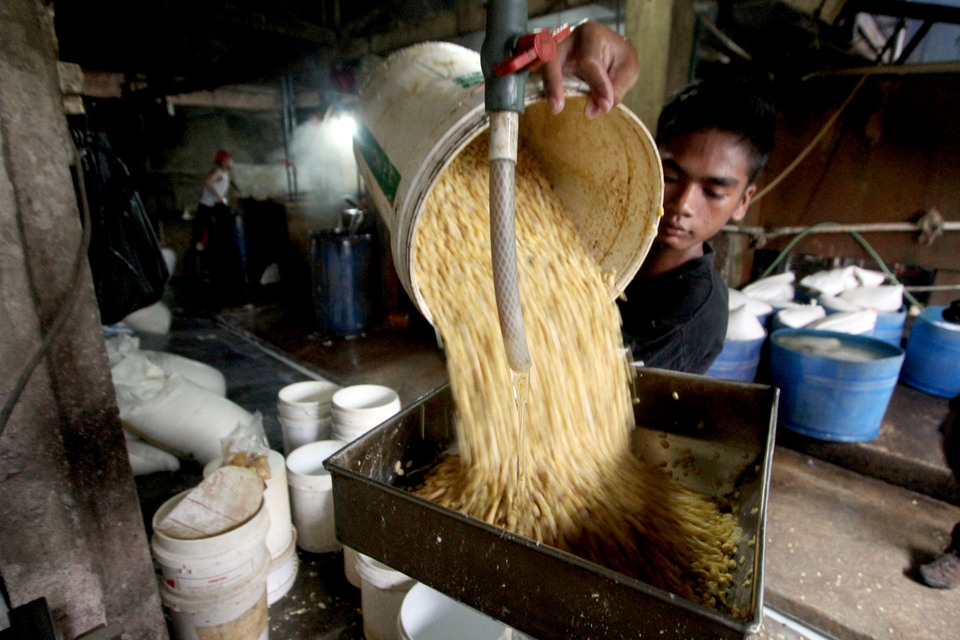 A worker loads soybeans into a pan at a tofu factory in Bogor, West Java. (Antara Photo)