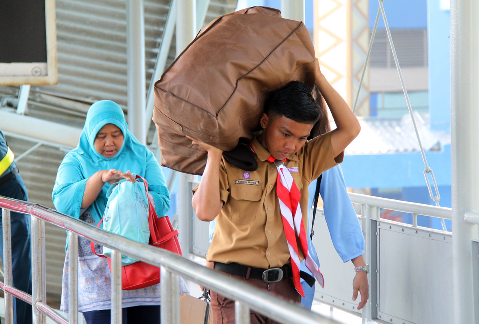 Pramuka (Scout) members assist travelers boarding roll-on-roll-off (Ro-Ro) ships at the Bakauheni crossing port in South Lampung, Lampung, Wednesday (20/6). Various volunteers from organizations including Scouts, the Red Cross, Health Department, are aiding travelers returning for the peak of the reverse migration flow, as predicted by Bakauheni ASDP to occur on June 20-21, 2018. (ANTARA FOTO/Ardiansyah).