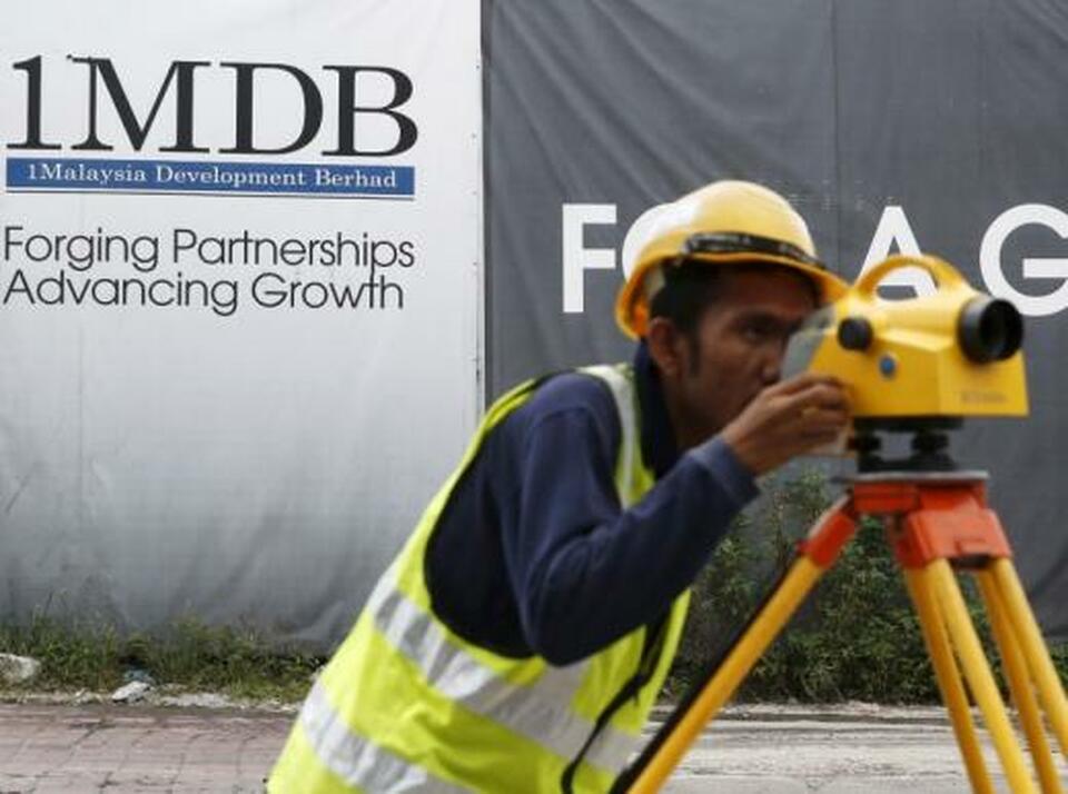 A construction worker works in front of a 1Malaysia Development Berhad (1MDB) billboard at the Tun Razak Exchange development in Kuala Lumpur, Malaysia. (Reuters Photo/Olivia Harris)