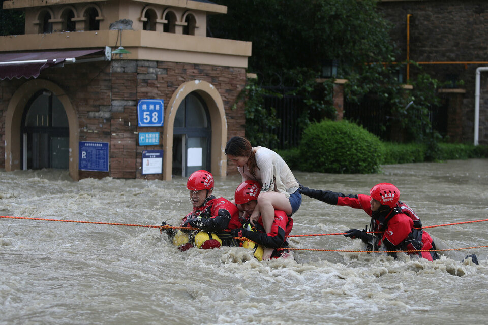 Firefighters rescue a stranded woman on a flooded street, following heavy rainfall in Chengdu, Sichuan province, China, Wednesday (11/07). (Reuters Photo/Wang Hongqiang)
