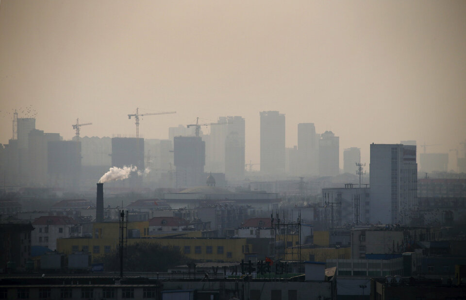 Smoke rises from a chimney among houses as new high-rise residential buildings are seen under construction on a hazy day in the city center of Tangshan, Hebei province. (Reuters Photo/Petar Kujundzic)