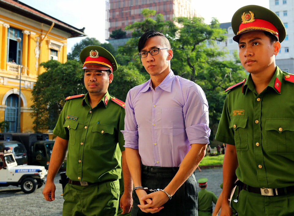 Will Nguyen, center, is escorted by policemen before his trial in Hồ Chí Minh City on Friday (20/07). (Reuters Photo)