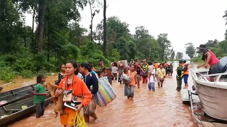 People walk through flooded area after being brought to safety by boat in Sanam Xay district, Attapeu Province, Laos after a hydropower dam under construction in Southern Laos collapsed, in this still picture taken from social media video obtained Tuesday (24/07). (Reuters Photo/ATTAPEU TODAY)