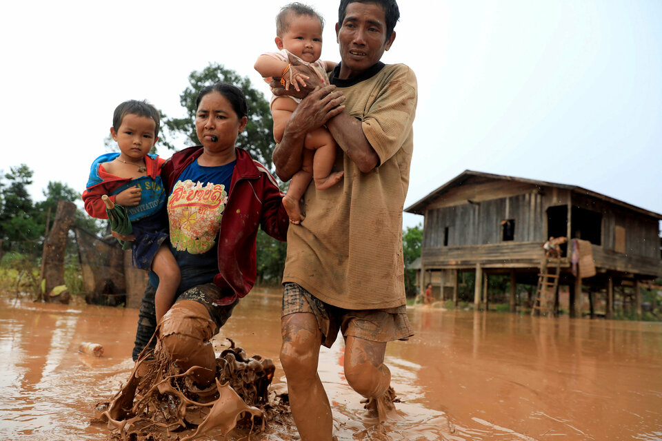 Parents carry their children as they leave their home during the flood after the Xepian-Xe Nam Noy hydropower dam collapsed in Attapeu province, Laos, Thursday (26/07). (Reuters Photo/Soe Zeya Tun)