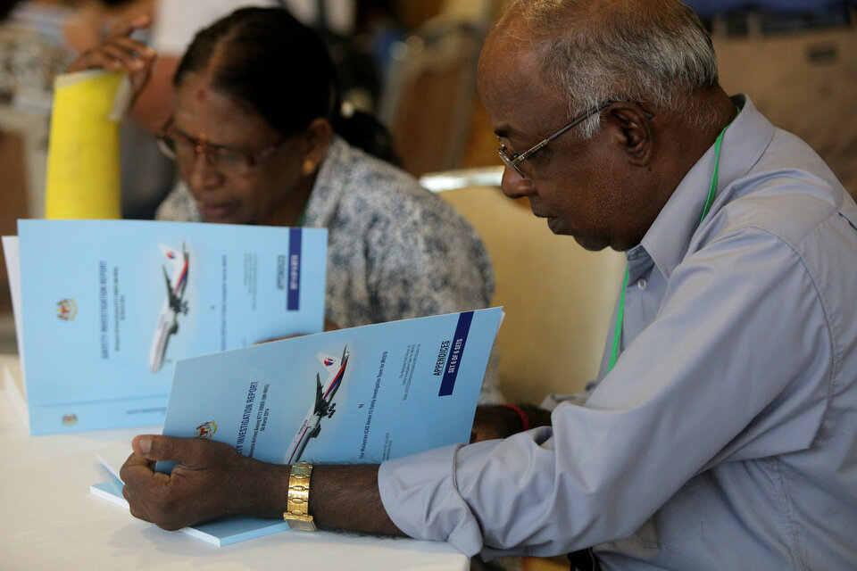 Family members read MH370 briefing reports before a closed door meeting in Putrajaya, Malaysia, Monday (30/07). (Reuters Photo/Sadiq Asyraf)