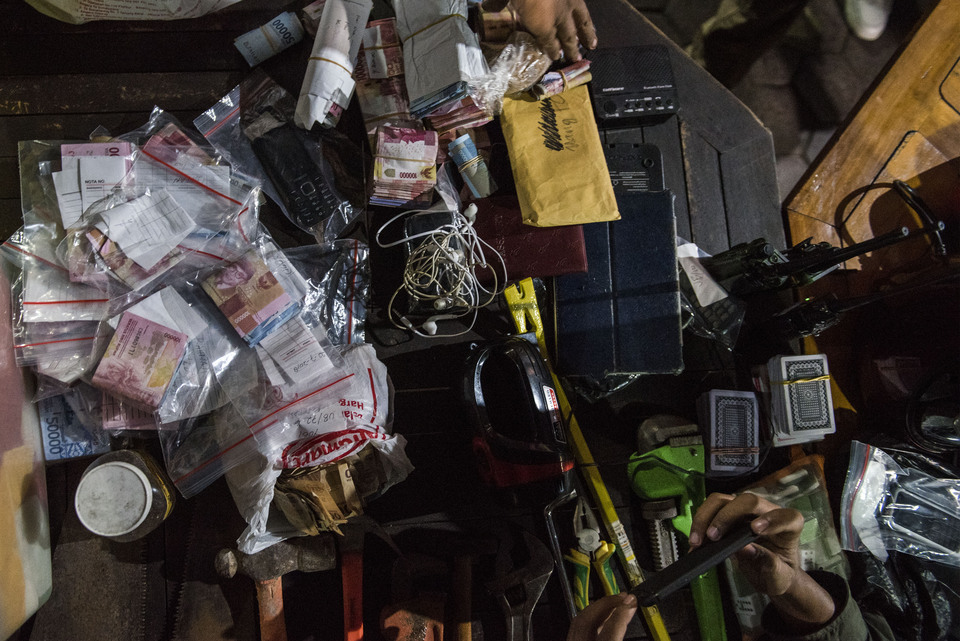 Officers arrange the goods and money seized from the Sukamiskin prison in Bandung, West Java, Sunday (22/07). The Ministry of Justice and Human Rights has ordered all prisons to be inspected amid a recent corruption scandal at the detention center. (Antara Photo/M Agung Rajasa)