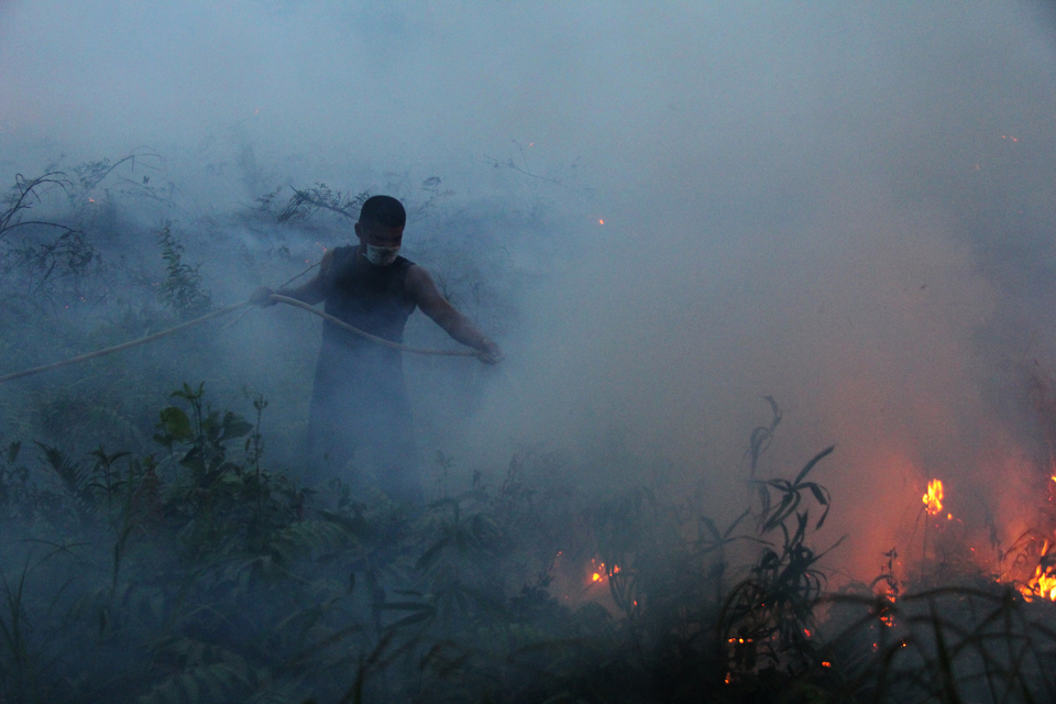 A resident tries to extinguish a fire in Dumai Barat, Dumai, Riau, on Tuesday (17/07). The region is notorious for forest and peatland fires. (Antara Photo/Aswaddy Hamid)