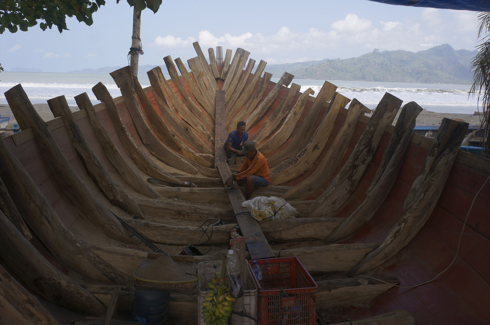 Workers complete a wooden fishing vessel on Sidem Beach, Tulungagung, East Java, on Friday (20/07). In addition to being cheaper, traditional wooden boats are more resilient at sea than those made in factories. (Antara Photo/Destyan Sujarwoko)