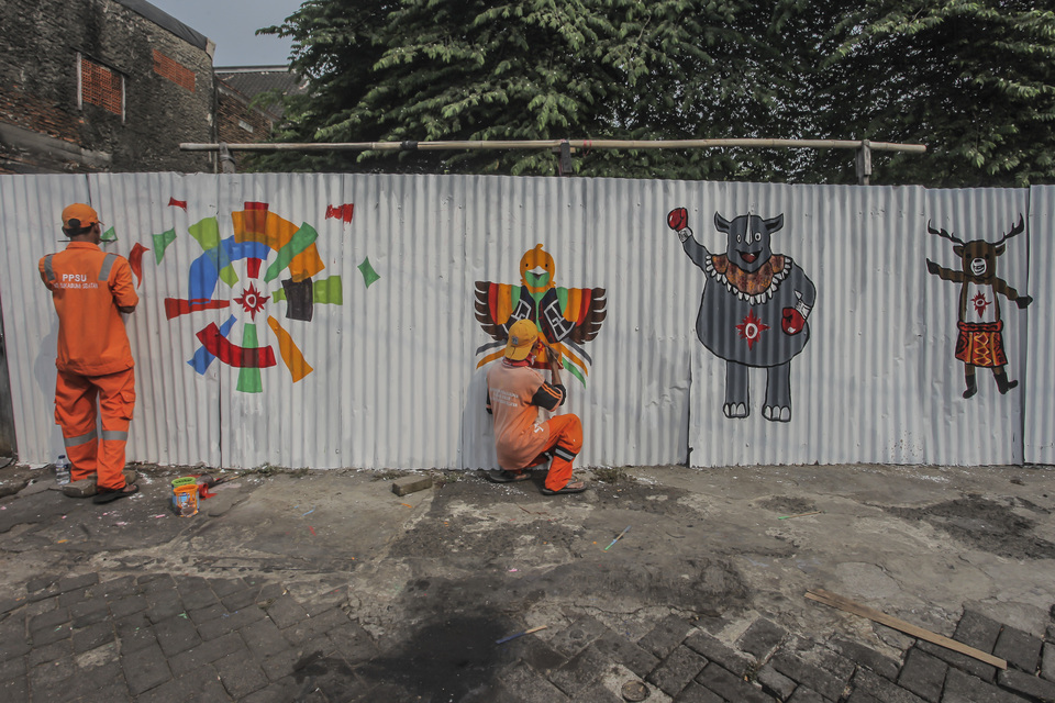 Workers paint Asian Games themes on a wall in Jakarta. (Antara Photo/Muhammad Adimaja)