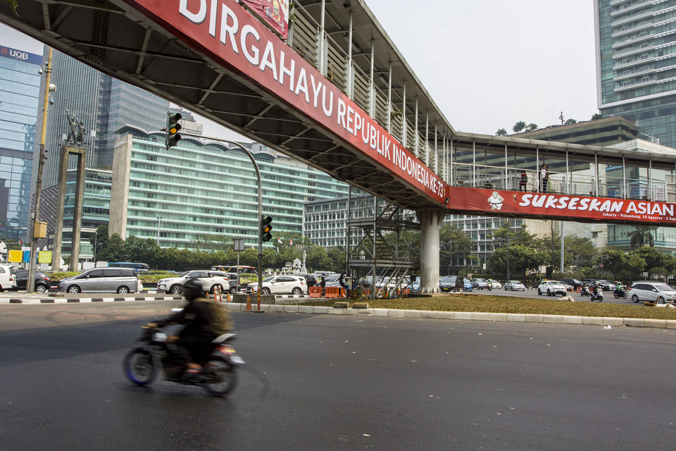 Motorists pass under a footbridge on the Hotel Indonesia traffic circle, Jakarta, Monday (23/07). Jakarta Governor Anies Baswedan said the bridge will soon be removed, as it blocks the view of the Welcome Monument. (Antara Photo/Galih Pradipta)