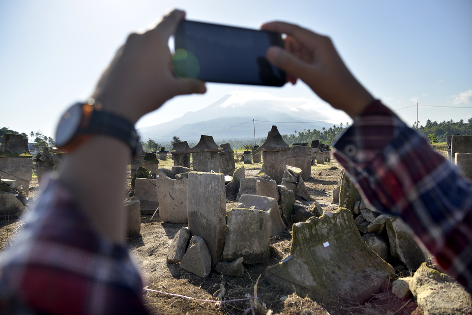 A visitor captures ancient graves in Waruga, Kolongan village, Kalawat, North Minahasa, North Sulawesi, Wednesday (18/07). Dozens of graves at the construction site of a dam and toll road have been badly damaged. (Antara Photo/Adwit B Pramono)