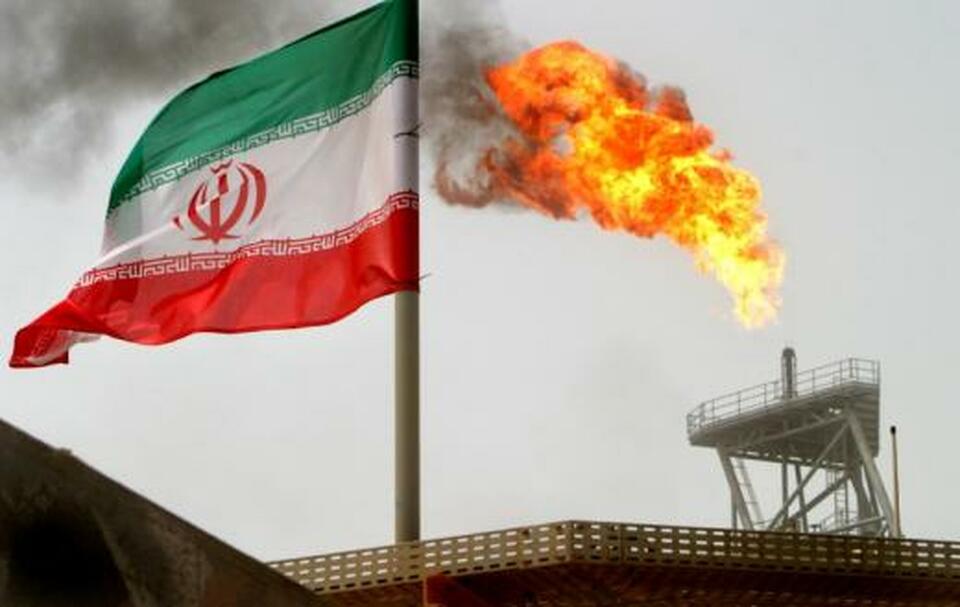 A gas flare on an oil production platform in the Soroush oil fields is seen alongside an Iranian flag in the Persian Gulf, Iran. (Reuters Photo/Raheb Homavandi)