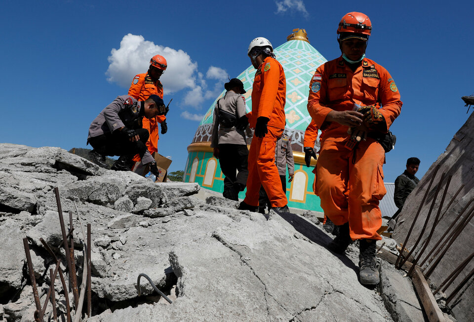 Rescuers and policemen walk on top of a collapsed mosque as they try to find survivors of Sunday evening's earthquake in Pemenang, Lombok, on Tuesday (07/08). (Reuters Photo/Beawiharta)