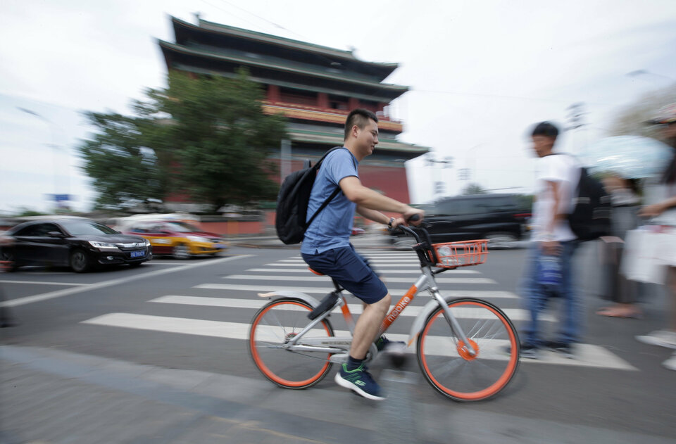 Mr. Gao, 28, cycles past the Drum Tower after a street interview on US-China trade war in Beijing, China, Aug. 9. (Reuters Photo/Jason Lee)