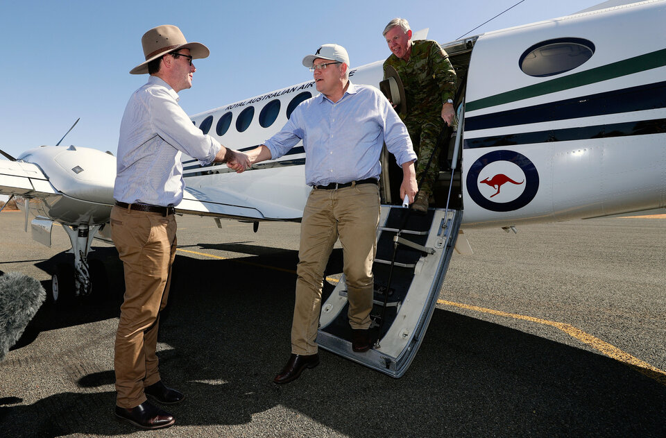 Australian Prime Minister Scott Morrison and National Drought Coordinator Maj.-Gen. Stephen Day are greeted by Australia's Minister for Agricultre and Water Resources David Littleproud after arriving at Quilpie in south-west Queensland, Australia, Monday (27/08). (Reuters Photo/AAP)