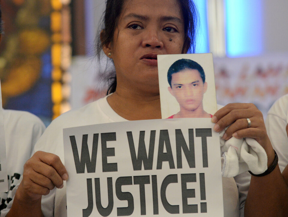 A woman displays a picture of her son, a drug war victim, and a placard during a protest against the war on drugs by President Rodrigo Duterte in Quezon city, Metro Manila, on Tuesday (28/08). (Reuters Photo/Eloisa Lopez)