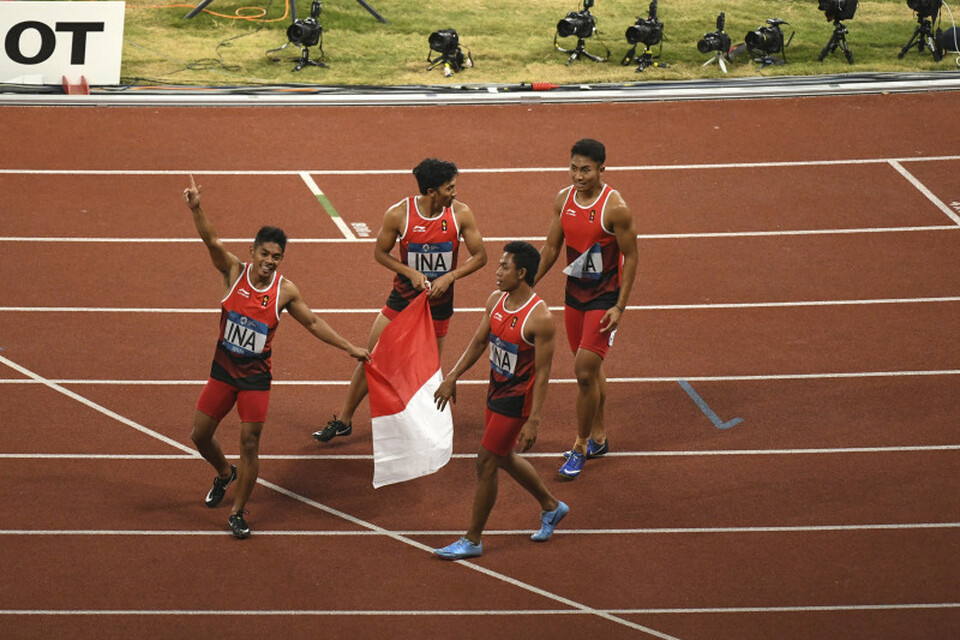 The Indonesian men's team, comprised of Fadlin, Lalu Muhammad Zohri, Eko Rimbawan and Bayu Kertanegara, carry the national flag after their second-place finish in the 4x400-meter relay at the Asian Games in Jakarta on Thursday evening (30/08). (Antara Photo/Inasgoc/Dwi Oblo)