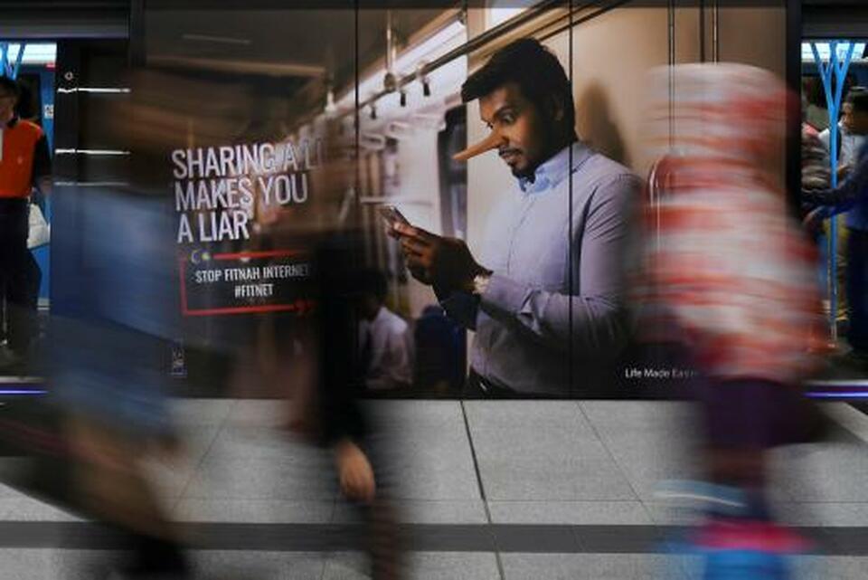 Commuters walk past an advertisement discouraging the dissemination of fake news at a train station in Kuala Lumpur in this March 28, 2018 file photo. (Reuters Photo)
