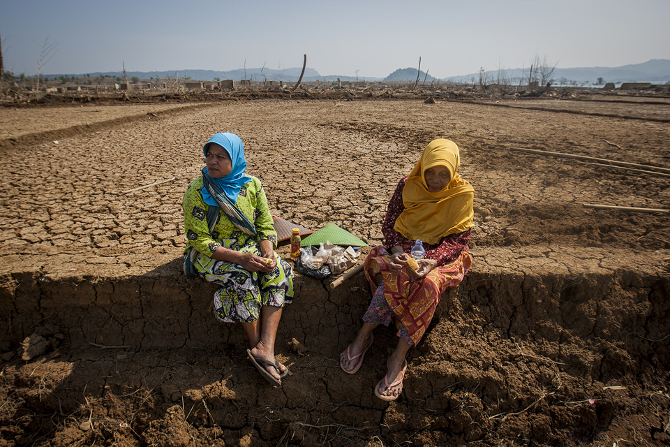 This file photo from 2018 shows two women sitting on their former rice field after a drought revealed the previously submerged plot of land in Jatigede Dam, Sumedang, West Java.  (JG Photo/Yudha Baskoro)