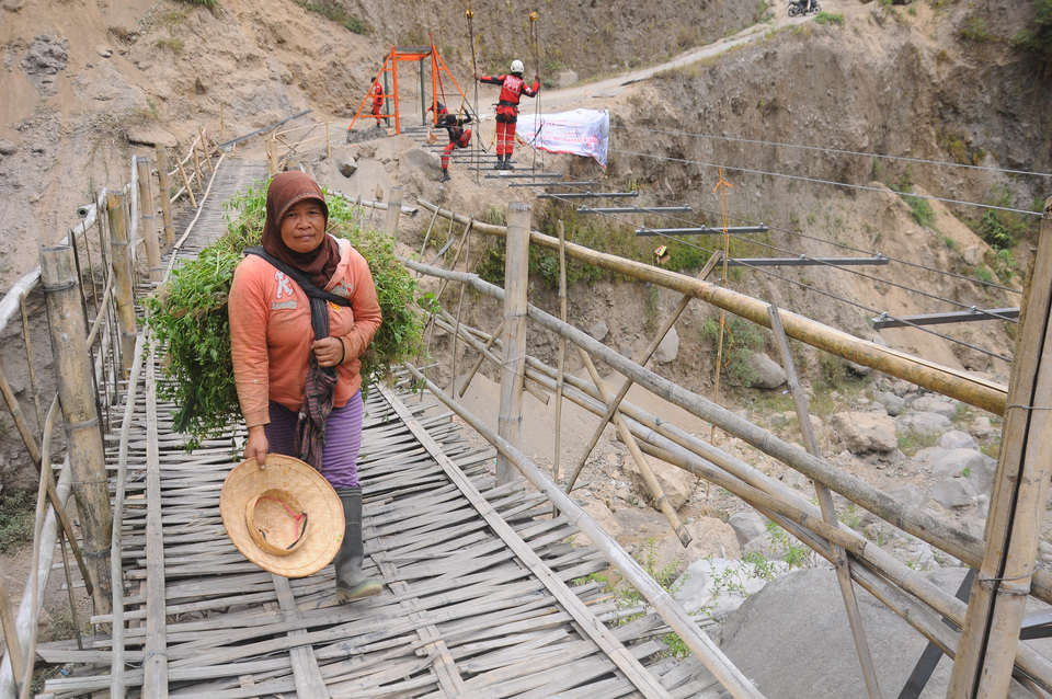 A woman crosses a bamboo bridge next to a suspension bridge under construction in Klakah, Boyolali district, Central Java, on Thursday (13/09). The suspension bridge is being built by the local community with donor funding from several communities to establish an evacuation route from the nearby Mount Merapi volcano as the existing bamboo bridge is considered unsuitable. (Antara Photo/Aloysius Jarot Nugroho)