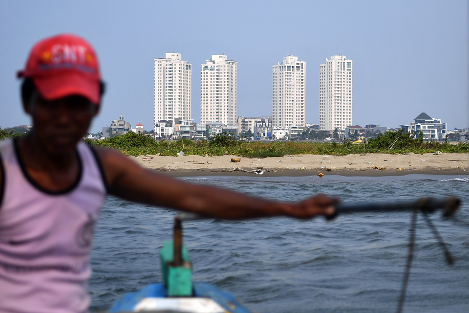 A fisherman photographed with Island G in the background in North Jakarta on Thursday (27/09). Jakarta Governor Anies Baswedan's surprise announcement a day earlier that he was revoking permits for 13 reclamation islands in Jakarta Bay has forced property developers working on the projects to reconsider their plans. (Antara Photo/Sigid Kurniawan)