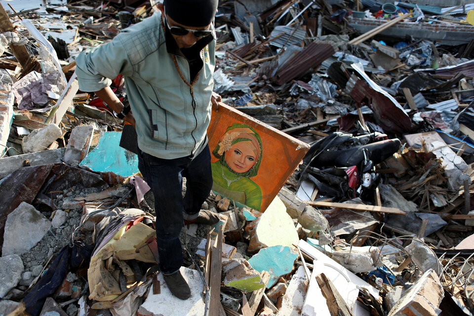 Agus Fardhan carries a portrait of his mother after he found it at her destroyed home in Palu, Central Sulawesi, on Sunday (07/10). (Reuters Photo/Jorge Silva)