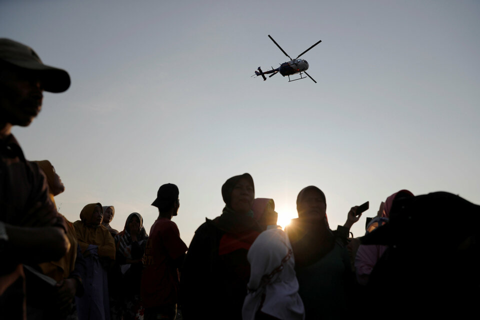 People watch a rescue team, as a helicopter flies overhead, to the location of the Lion Air flight JT610 crash site off the coast of Karawang regency, West Java province Indonesia, October 29, 2018. REUTERS/Beawiharta