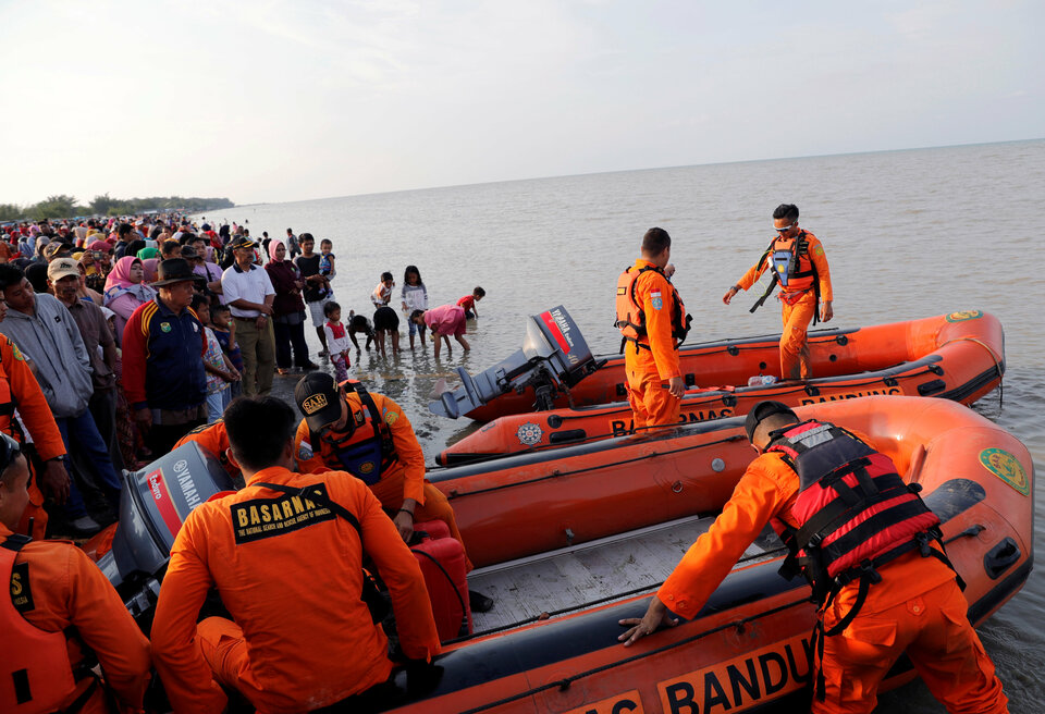 People watch on the beach, as a rescue team prepares their boat before departing to the Lion Air flight JT610 crash site off the coast of Karawang district, West Java, on Monday. (Reuters Photo/Beawiharta)