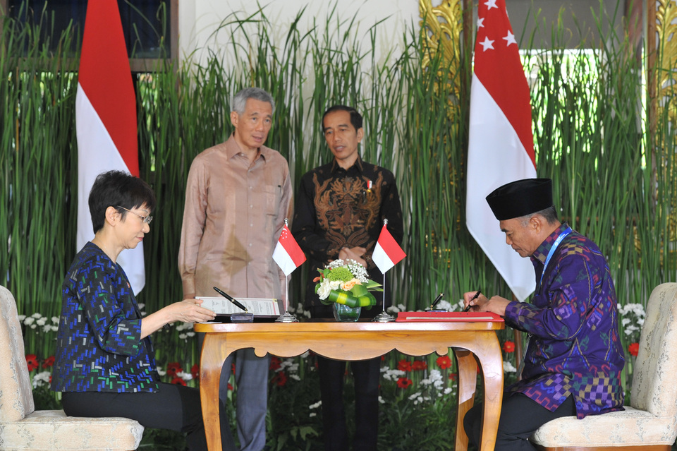 President Joko 'Jokowi' Widodo and Singaporean Prime Minister Lee Hsien Loong, back left, witness the signing of a currency swap agreement on the sidelines of the 2018 Annual Meetings of the International Monetary Fund and World Bank Group in Nusa Dua, Bali, on Thursday. (Antara Photo/Veri Sanovri)