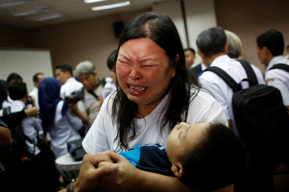 A woman, whose husband was on Lion Air flight JT-610, cries as she holds their son after a news conference about the recovery process in Jakarta on Monday. (Reuters Photo/Willy Kurniawan)