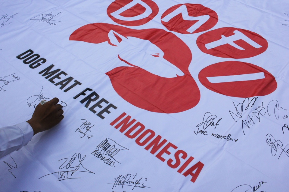 A resident signs a banner during a campaign against dog meat at Apsari Park in Surabaya, East Java, on Sunday. Organizers called on the community to demand a total ban on the sale of dog and cat meat in Indonesia. (Antara Photo/Didik Suhartono)