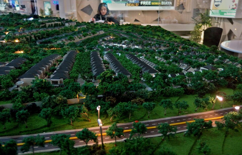 A booth attendant stands near a miniature model of a residential area at the Real Estate Indonesia (REI) property exhibition in Semarang, Central Java, Nov. 16, 2018. (ANTARA PHOTO/R. Rekotomo)