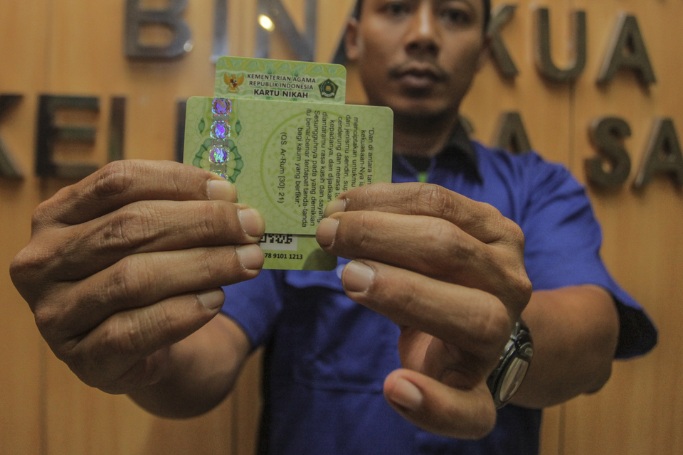 An official displays samples of new marriage cards at the offices of the Ministry of Religious Affairs in Jakarta on Monday. The cards will be issued in addition to the current marriage booklets from the end of this month to eradicate rampant forgery of the latter. Besides photos of the legally married couple, each card will also have a QR code that can be scanned to show additional information. (Antara Photo/Muhammad Adimaja)