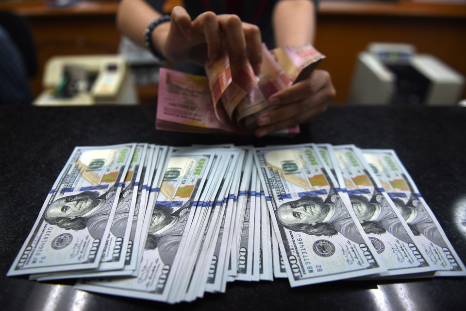 An officer counts rupiahs and dollars in a money changer in Jakarta. (Antara Photo/Akbar Nugroho Gumay)