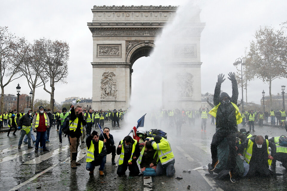 Protesters wearing yellow vests, a symbol of a French drivers' protest against higher diesel taxes, stand up in front of a police water canon at the Place de l'Etoile near the Arc de Triomphe in Paris, France on Saturday. (Reuters Photo/Stephane Mahe)