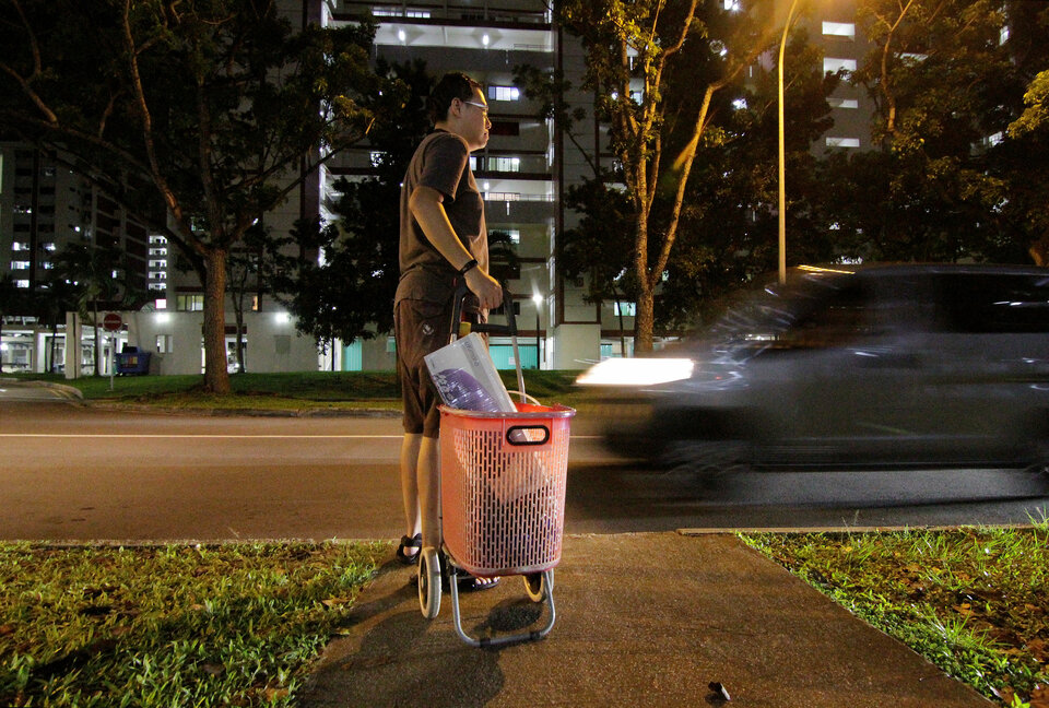 Freegan Daniel Tay waits to cross the road while dumpster diving, next to his makeshift trolley carrying a massager that he found, in Singapore November 17, 2018. Picture taken November 17, 2018. (Reuters Photo/Natashia Lee)