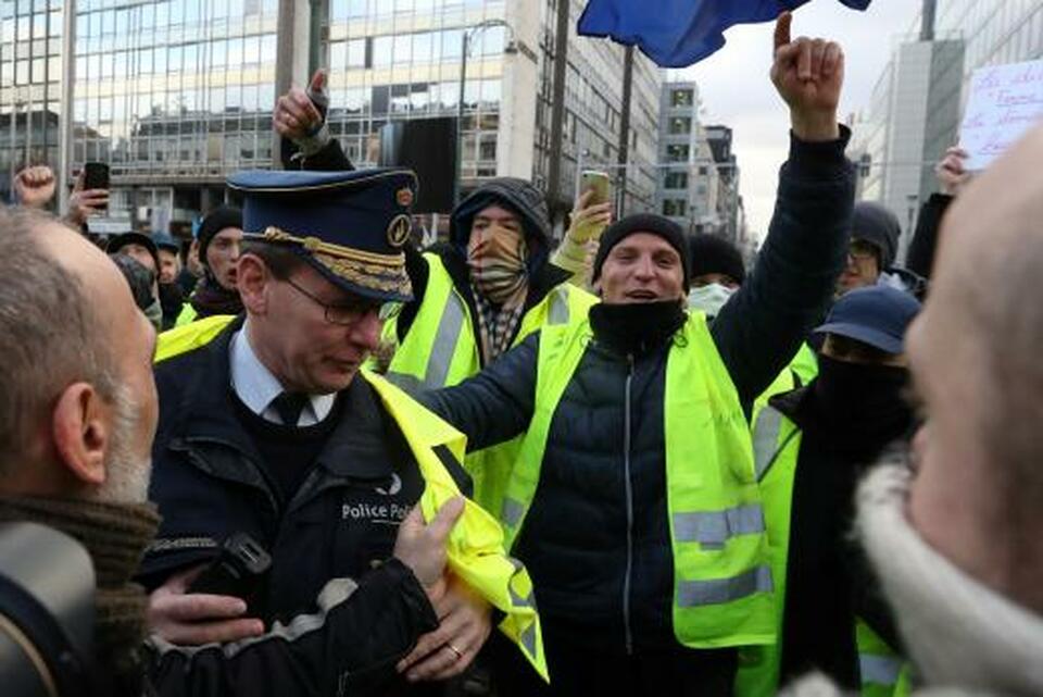 Protesters wearing yellow vests, a symbol of a drivers' protest against higher fuel prices, put a yellow vest on a policeman during a demonstration in central Brussels, Belgium, on Nov. 30, 2018. (Reuters Photo/Yves Herman)