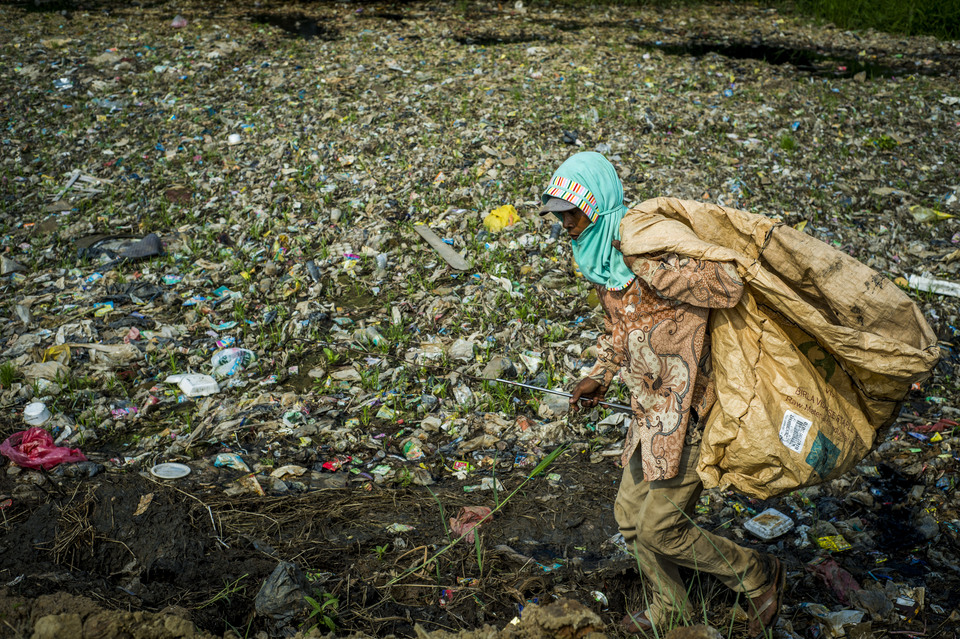 A man collects plastic waste from a heavily polluted river in Bekasi, West Java, in this January 2019 file photo. The House of Representatives wants industries to respond to the government's tax on plastic shopping bags by creating more environmentally friendly alternatives. (JG Photo/Yudha Baskoro)