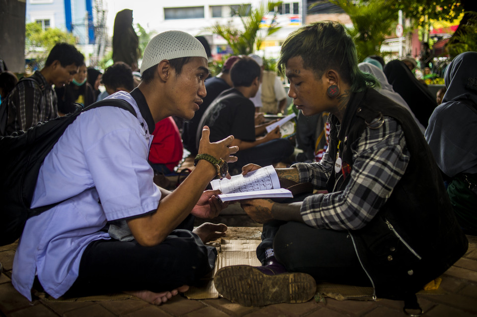 A street punk and a Muslim cleric study the Koran together underneath an overpass near the Tebet railway station in South Jakarta on Dec. 21, 2018. (JG Photo/Yudha Baskoro)