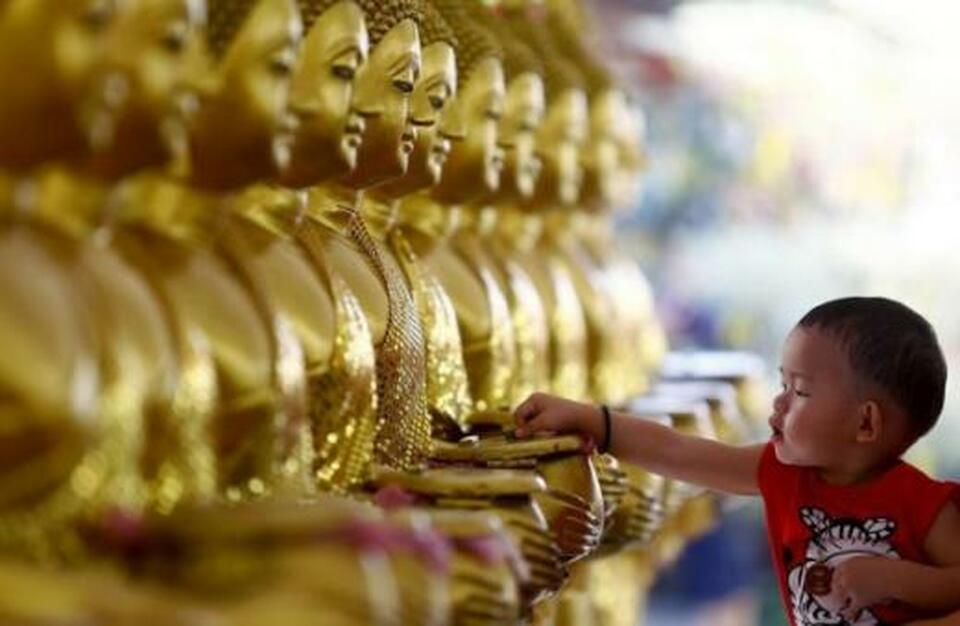 A child touches Buddha statues in Tibet. (Reuters Photo)