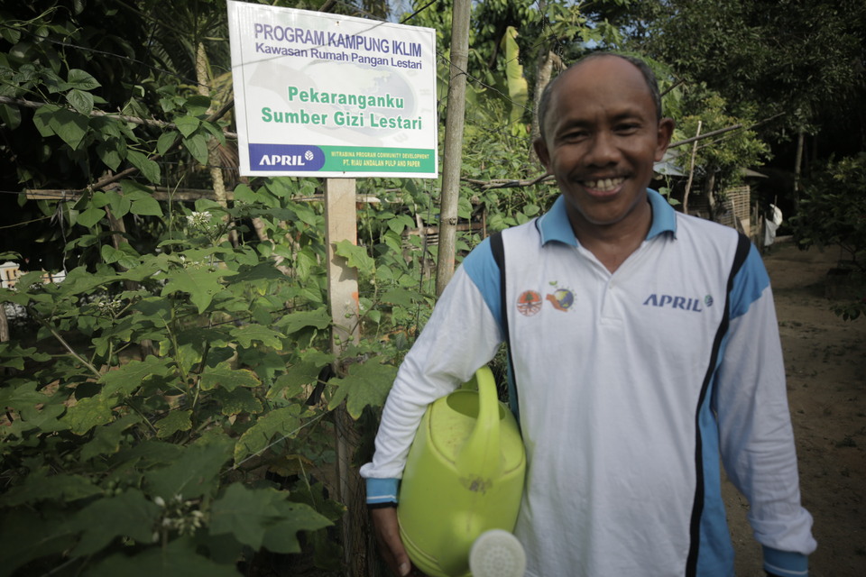 A resident of Gunung Sari village in Kampar district, Riau, poses for a photo in front of his garden used to grow crops as part of the Climate Village Program. (Photo courtesy of RAPP)