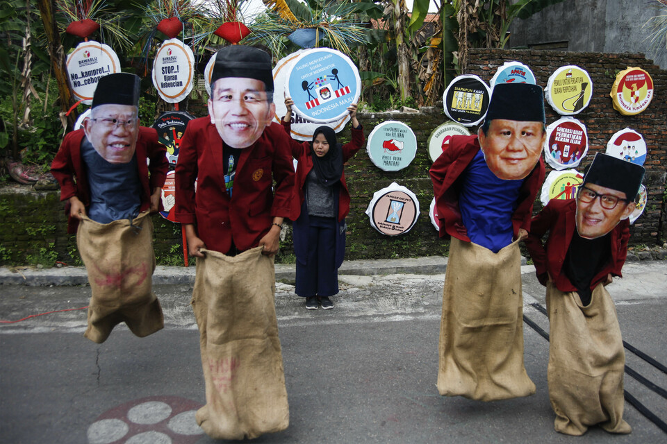 Students wearing Jokowi and Prabowo masks play a game of sack race in Solo, Central Java. (Antara Photo/Maulana Surya)