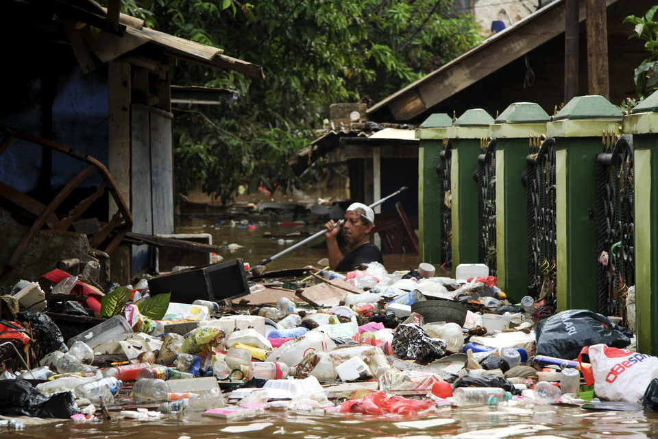A resident tries to clear garbage that washed up outside his home after the Ciliwung River broke its banks in Cililitan Kecil, East Jakarta, in April. (Antara Photo/Risky Andrianto)