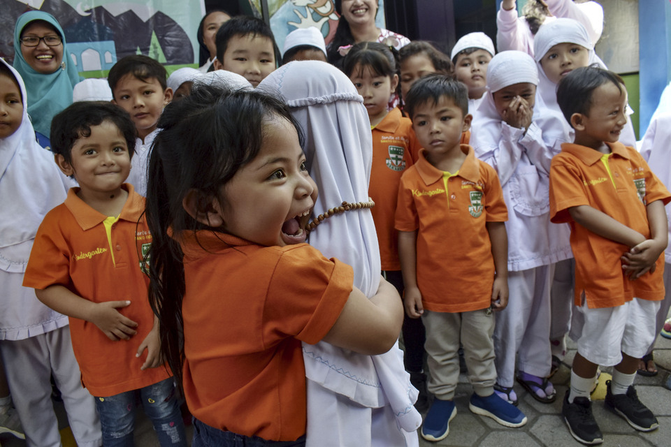 FILE - A Saint Bernardus kindergarten student, left, hugs a student from Aisyiyah Bustanul Athfal Islamic kindergarten as they visit the school during Ramadan in Madiun, East Java, on Thursday, May 9, 2019. The visit is intended to teach children about the importance of religious tolerance and sharing among people of different faiths. (Antara Photo /Siswowidodo)